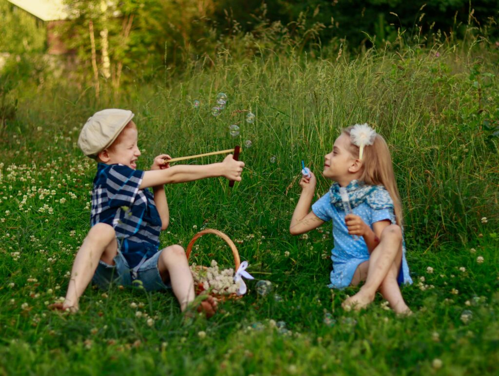 Kids enjoying a sunny summer day blowing bubbles in a lush green meadow.
