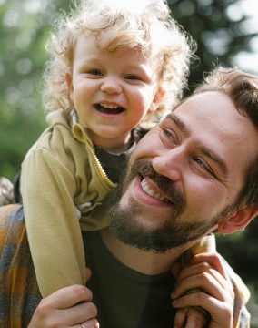 A joyful moment captured with a father and his son smiling in an outdoor setting.