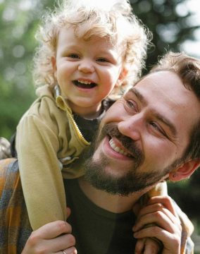 A joyful moment captured with a father and his son smiling in an outdoor setting.