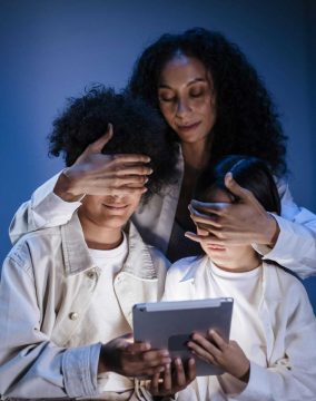 A mother supervises two children using a tablet, promoting digital safety and responsible media use.